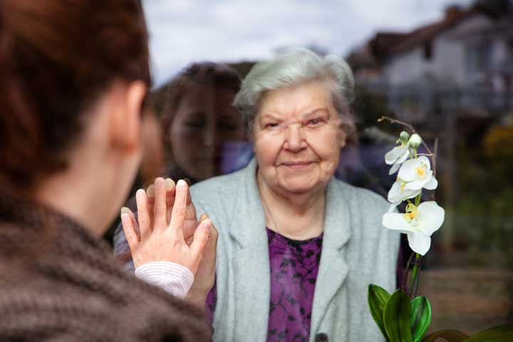Ältere Dame mit grauen Haaren reicht einer jungen Frau die Hand.