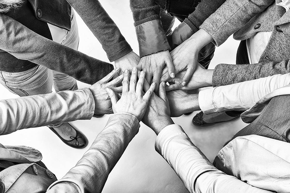 Mehrere Menschen stehen im Kreis und legen die Hände zusammen.
