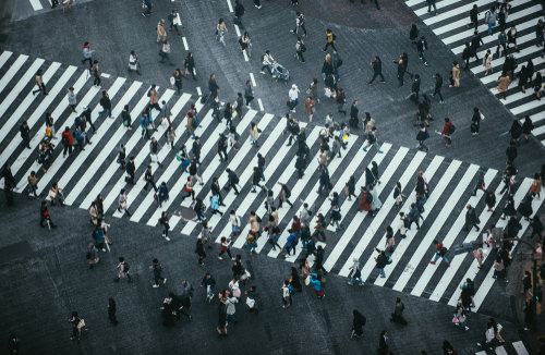 Menschen laufen auf einer großen Kreuzung über einen Zebrastreifen