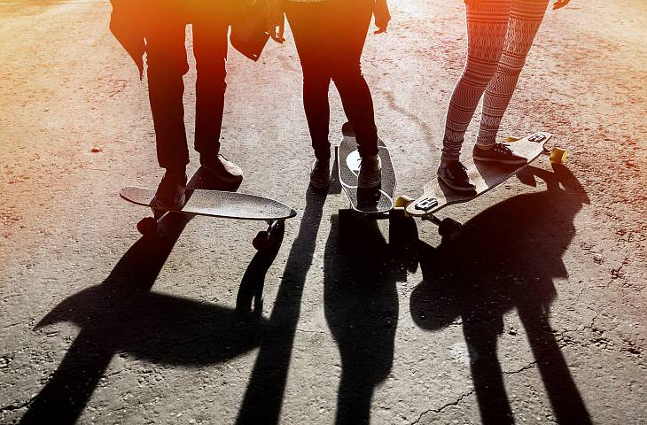 Drei Jugendliche stehen mit dem Skateboard auf der Straße