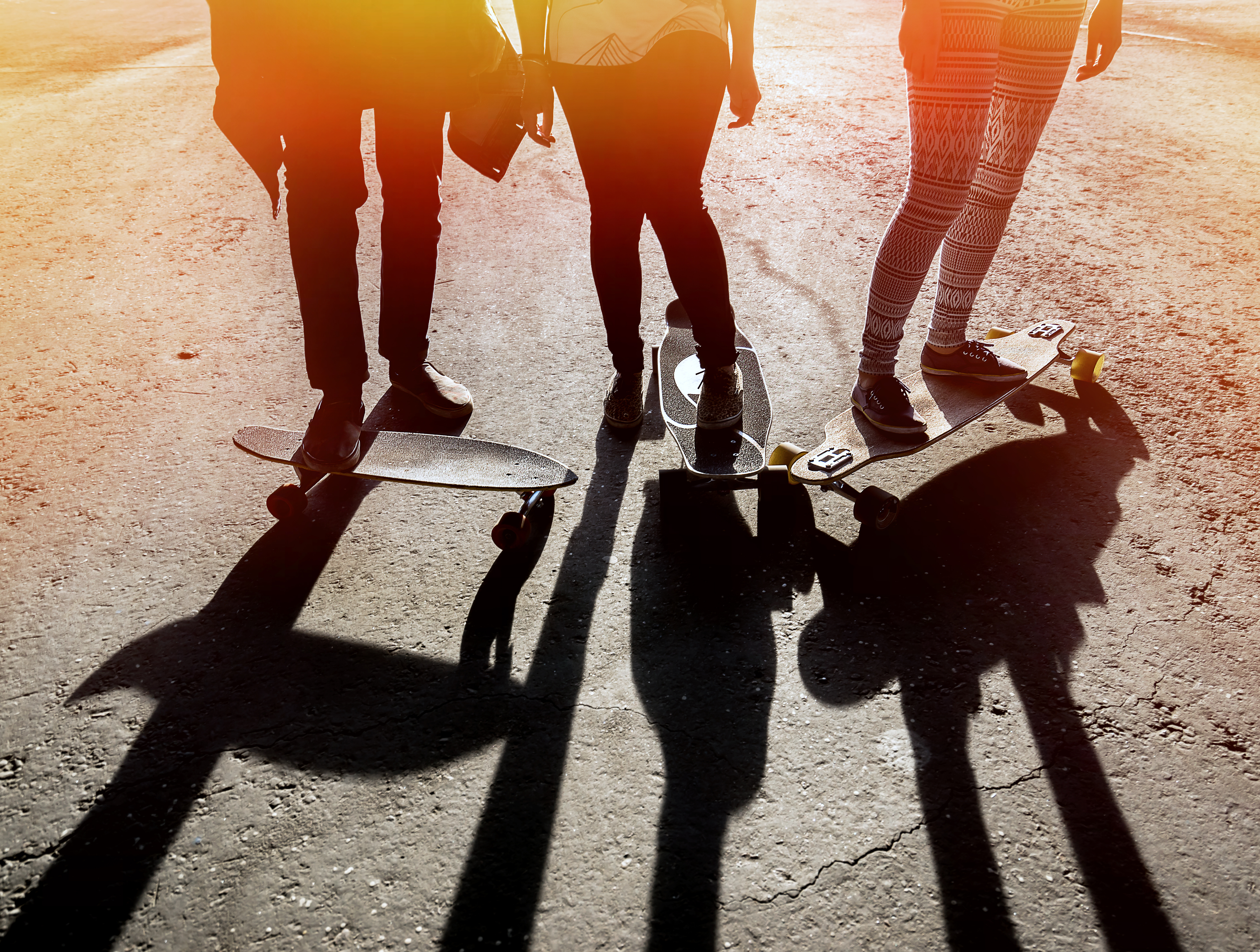 Drei Jugendliche stehen mit dem Skateboard auf der Straße