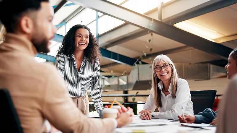 Junge Frau die vor einem Team steht und einen Vortrag hält.