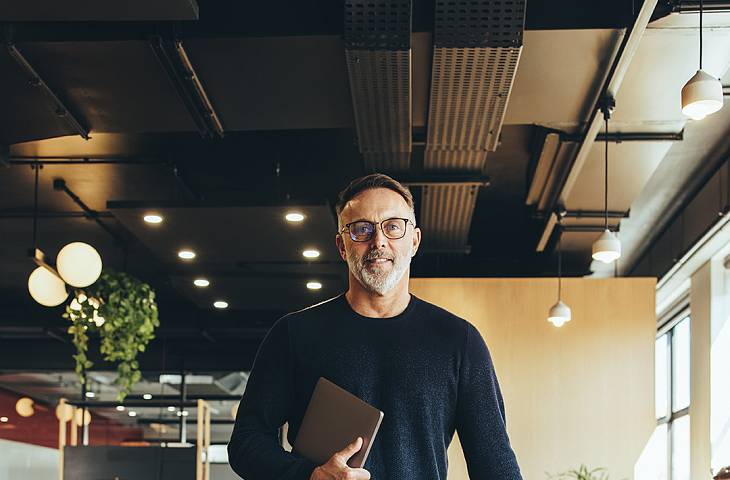 Personen stehen am Tisch und unterhalten sich freudig. ein Laptop steht auf dem Tisch.