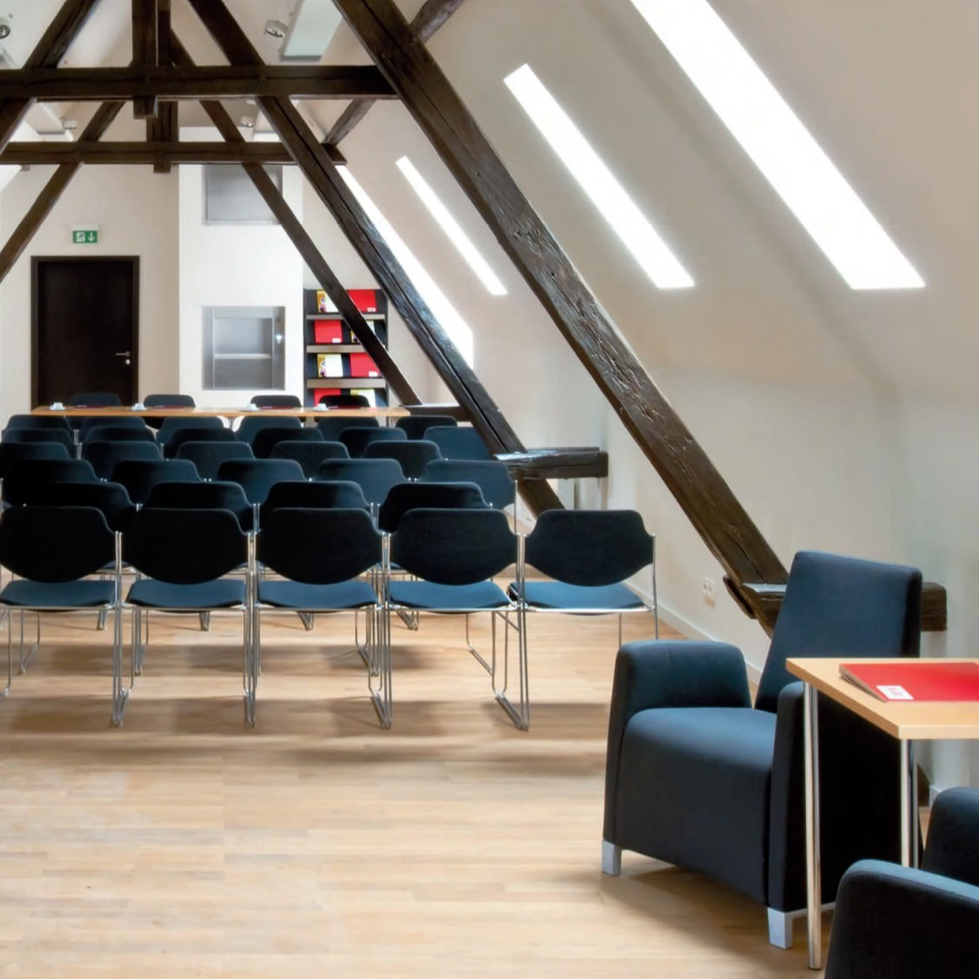 Heller Veranstaltungsraum im Frankfurter PresseClub mit Holzbalken, Stuhlreihen und modernem Sitzbereich unter Dachschrägen