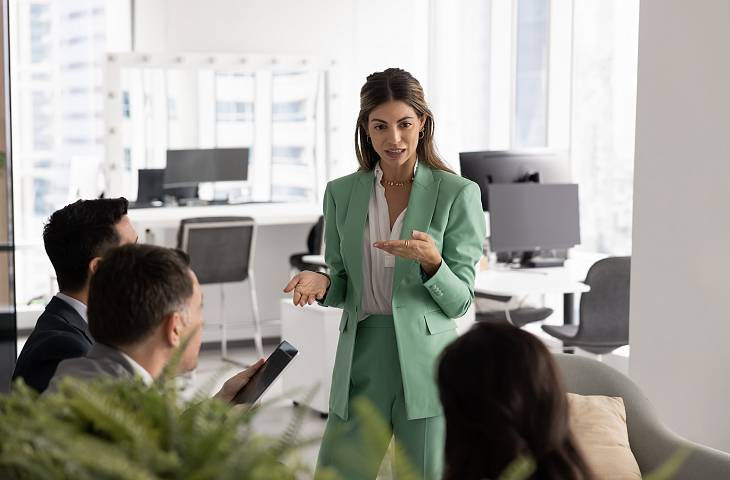 Junge Führungskraft bespricht Strategie und Entscheidungen mit Kollegen im modernen Büro während eines Meetings
