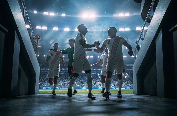 Fußballmannschaft läuft gemeinsam aufs Spielfeld und feiert den Teamgeist.